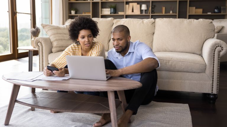 couple paying bills online and calculating expenses at home